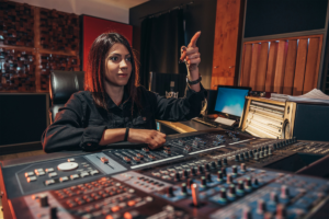 Young woman music producer working on a mixing soundboard while in her studio_images-1200x800